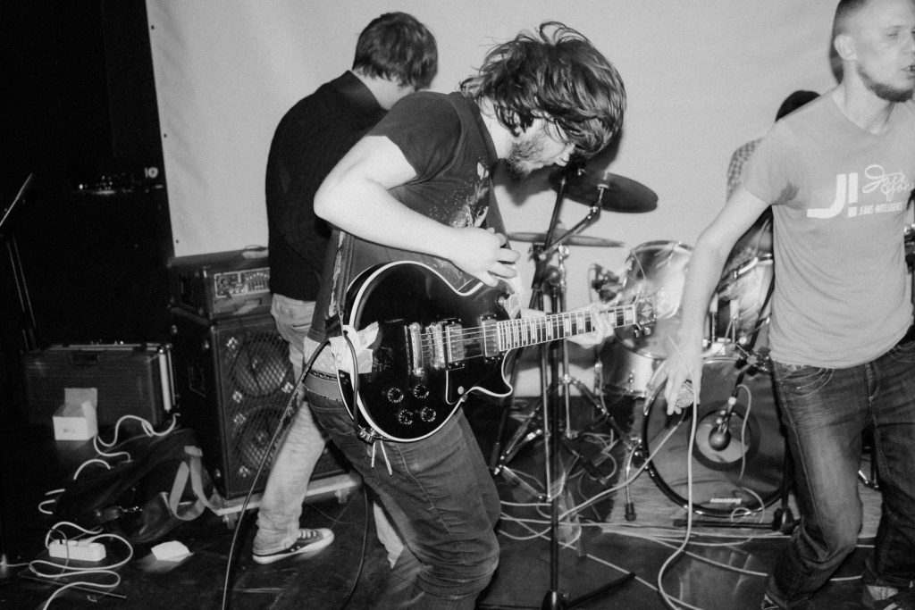Band playing live, with a guitarist front and centre